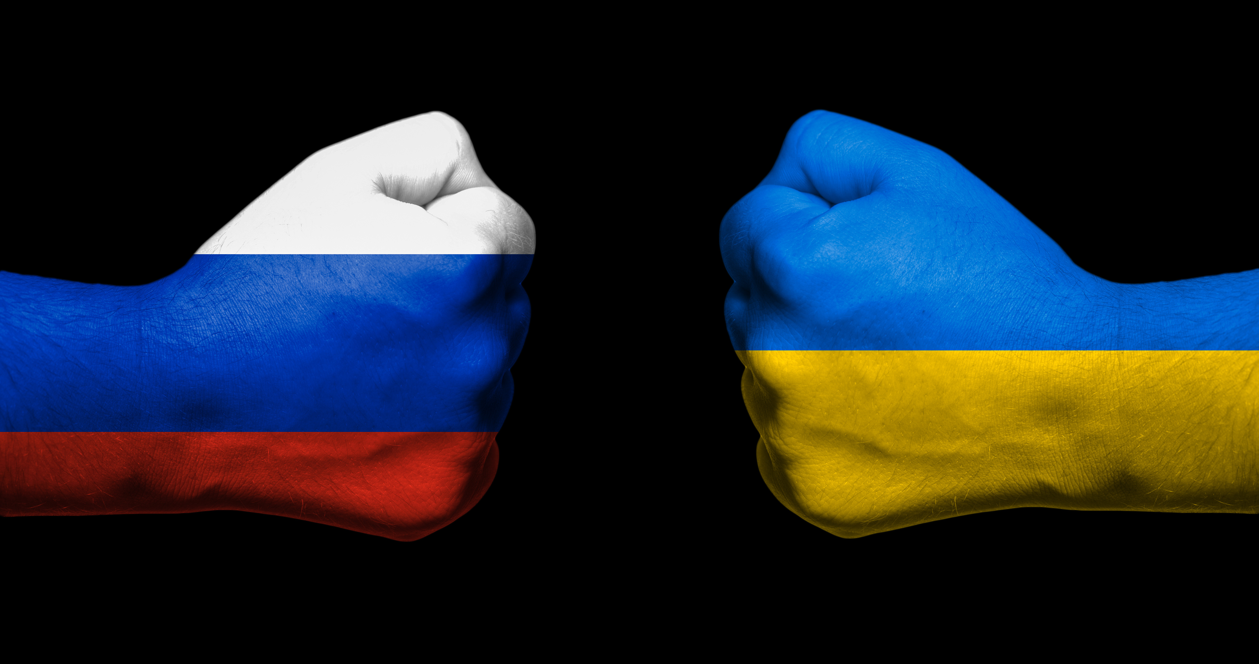 Flag of Ukraine and Russia painted on two clenched fists facing each ...